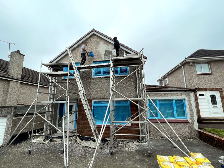 Team applying render from scaffold on a two-storey house